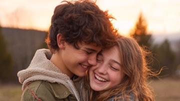 Zwei Teenager (ein Junge und ein Mädchen) lächeln eng und mit offensichtlicher Komplizenschaft. Mit KI erstelltes Bild.